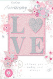 This anniversary card is shown in a close, detailed view, its design unfolding like a whispered declaration of love suited to Coulsdon's calm, residential charm. The central focus is the word LOVE, spelled out in soft, raised glitter that gives each letter a subtle three-dimensional form. The glitter is predominantly pale with a silvery sheen, and the letter O is transformed into a shimmering heart accented in textured silver, immediately drawing the eye. Surrounding this centrepiece, a halo of delicate blooms unfurls in blush, mauve, and pastel pink, their edges softened as though painted in gentle watercolour washes. The petals and leaves are connected by fine, flowing lines that curve and loop, suggesting motion and a sense of care, much like the thoughtful placement of each stem in an anniversary bouquet. Tiny flourishes-small petals, swirling accents, and almost translucent butterflies-add an element of lightness and whimsy, reminiscent of an English spring garden not far from Coulsdon's leafy avenues. At the top and bottom, the phrases On Our Anniversary and I love you today and always are set in an understated, elegant script that echoes the curves of the floral artwork. The composition as a whole carries a tender, intimate mood, ideal for marking a shared journey. It is easy to imagine this card arriving alongside a hand-delivered arrangement from a local Coulsdon florist, the soft colours and tactile details turning a simple message into a cherished keepsake that can be revisited year after year.
